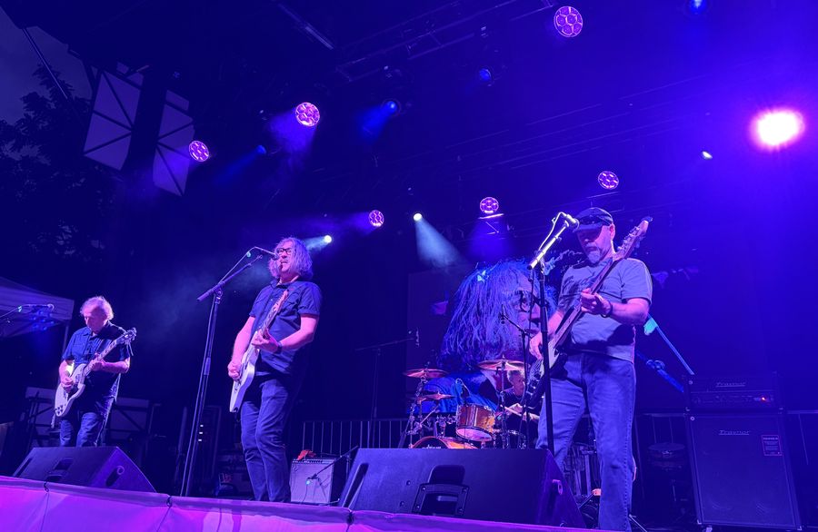 The band in purple light, guitarists and bassist up front with the drummer behind
