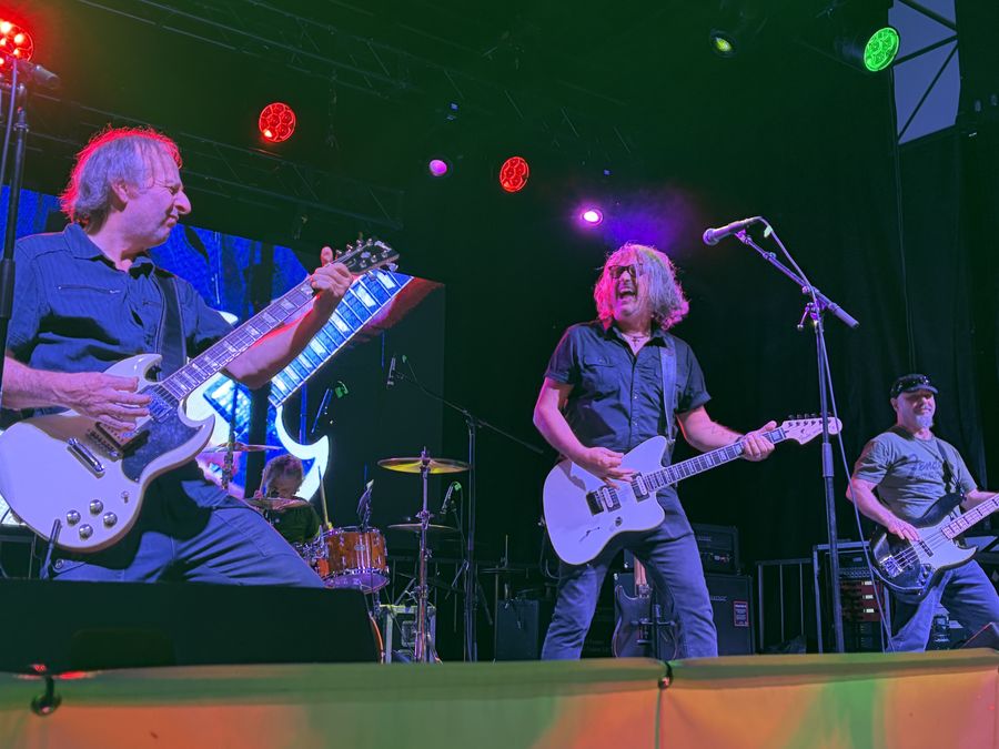 Guitarist and singer face off mid-song in a red and orange stage glow